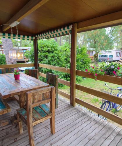 Holzveranda mit rustikalem Tisch und bunten Blumen.