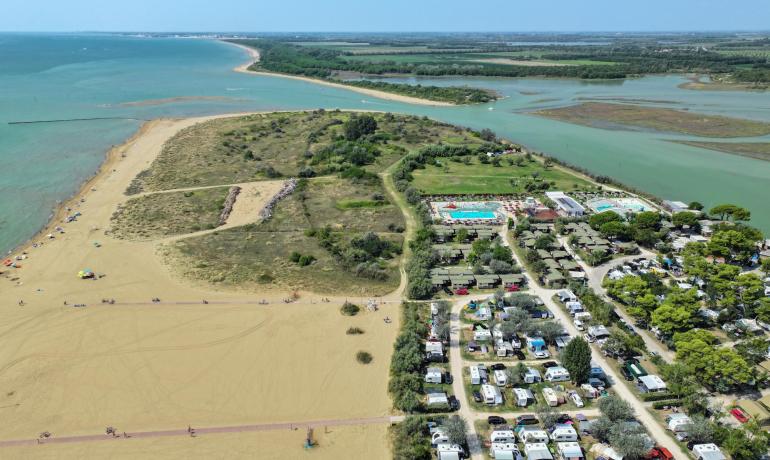 Aerial view of beach, campsite, and pool near the sea.