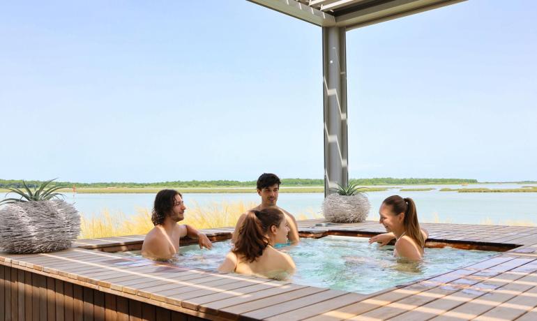 People relaxing in a hot tub with a lake view.