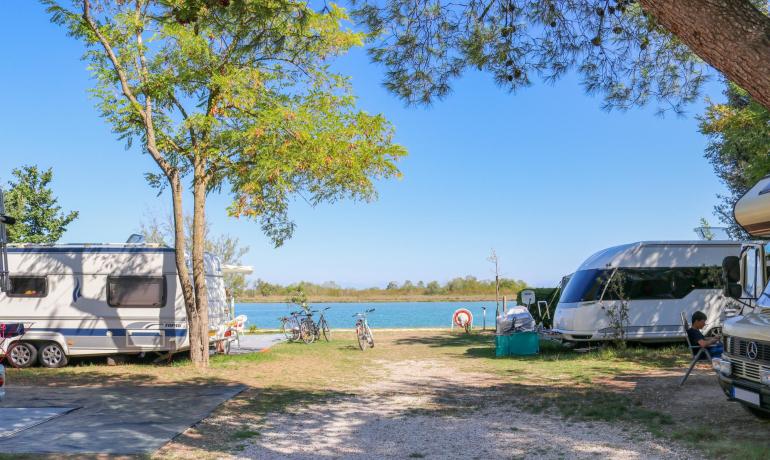 Camping mit Wohnwagen am See, geparkte Fahrräder.