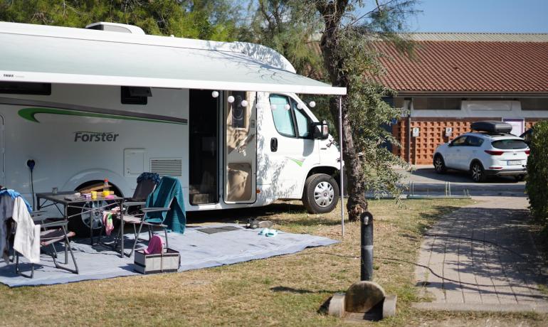 Parked camper with outdoor picnic area, sunny day.