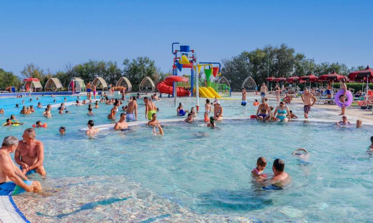 Crowded pool with colorful slides and families having fun.