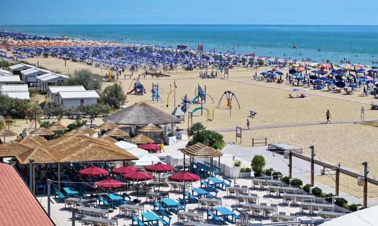 Travl strand med farverige parasoller og strandfaciliteter.