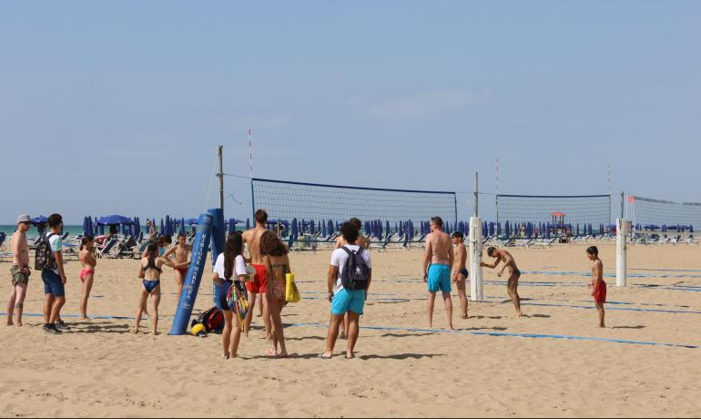 Young people play beach volleyball on a sunny beach.