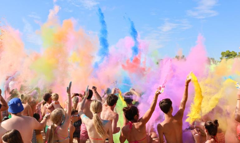 Buitenfeest met kleurrijke poeders in de lucht.