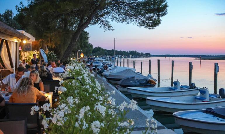 Buitenrestaurant bij zonsondergang, uitzicht op het meer en boten.